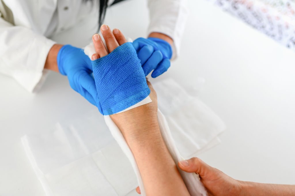 Closeup of the hands of doctor bandaging a patient's arm at doctor's office